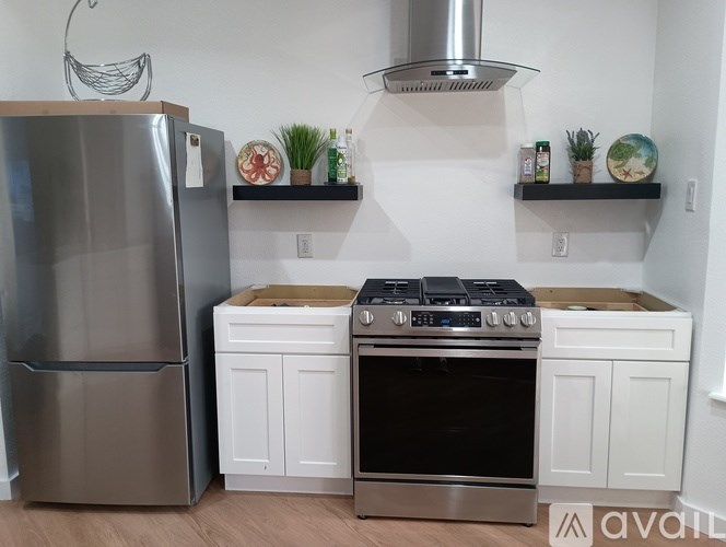 A kitchen with a stainless steel refrigerator, a stove with a black top, and a white oven.