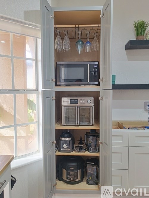 A kitchen cabinet with a microwave, oven, and coffee maker.