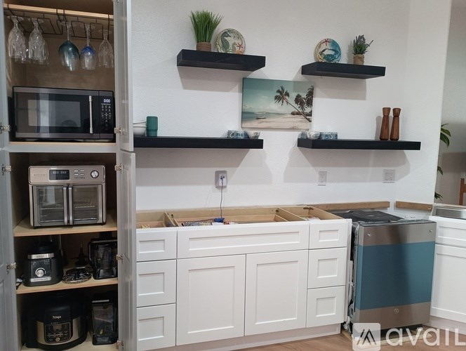 A kitchen with white cabinets and black shelves.