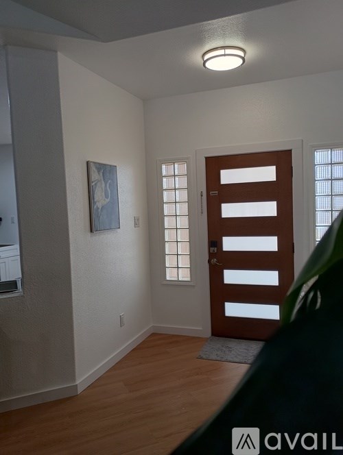 A room with a brown door and a painting on the wall.