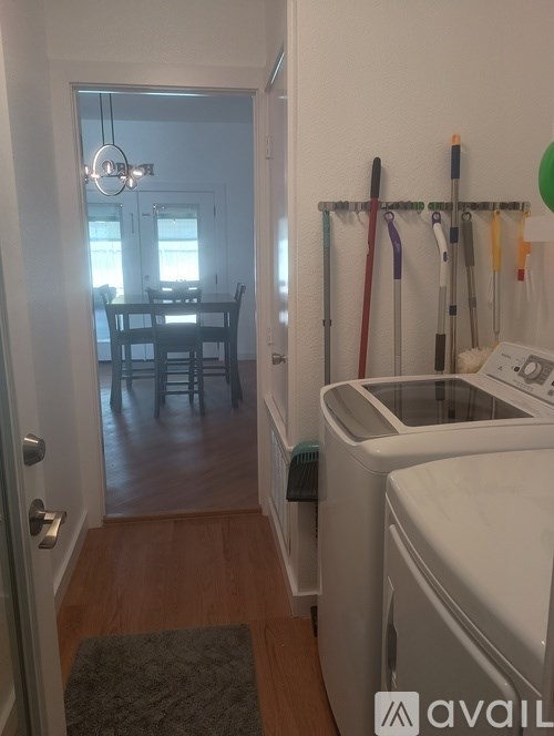 A laundry room with a washer and dryer and a dining room in the background.