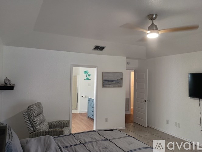 A bedroom with a bed, chair, and a ceiling fan.