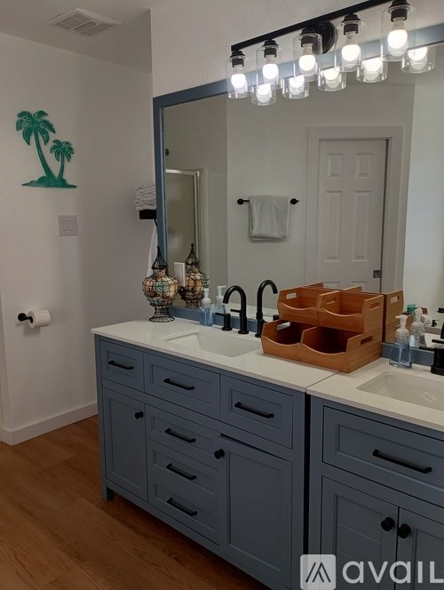 A bathroom with a sink, mirror, and a palm tree decal on the wall.