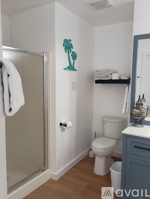 A bathroom with a toilet, a sink, and a wall decal of a palm tree.