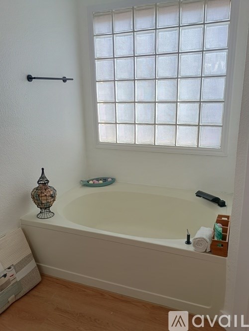 A white bathroom with a tub and a window.