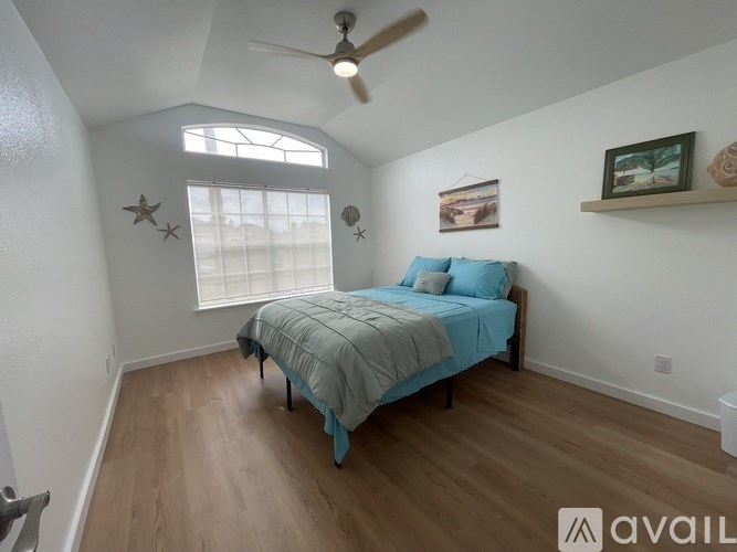 A bedroom with a bed, a ceiling fan, and a window.