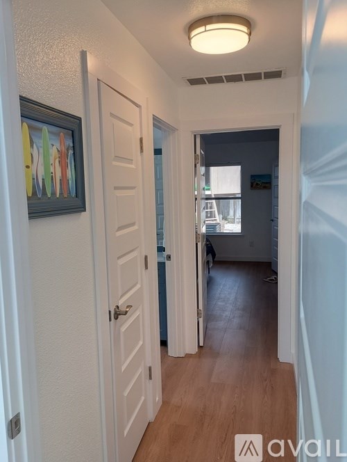 A hallway with a white door and a painting on the wall.