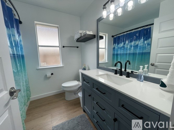 A bathroom with a toilet, sink, and mirror.