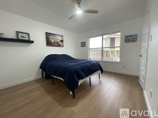 A bedroom with a bed, a ceiling fan, and a window.