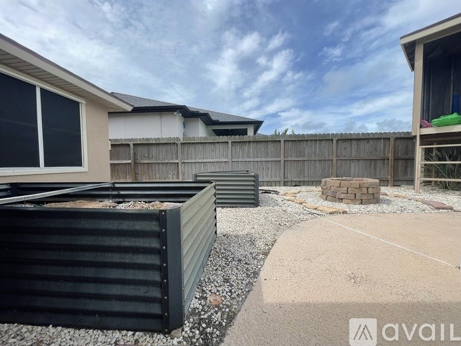 A backyard with a wooden fence and a gravel area.