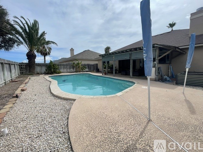 A pool surrounded by a gravel area and a wooden fence.
