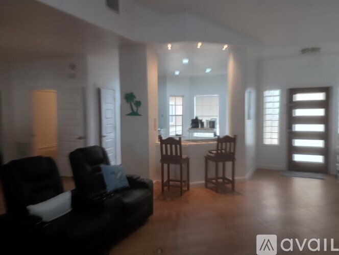 A living room with a black couch and wooden floors.