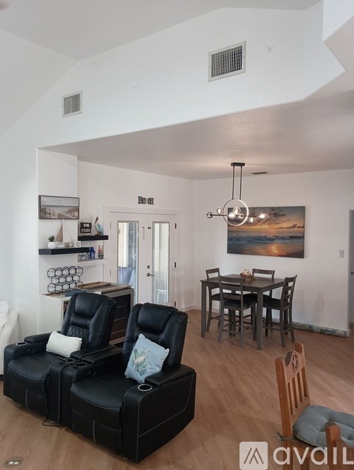 A living room with black leather chairs and a wooden table.