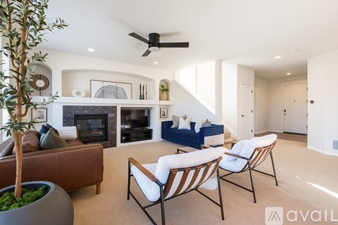 A living room with a fireplace, two chairs and a couch.