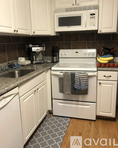 A kitchen with white cabinets and a white stove top oven.