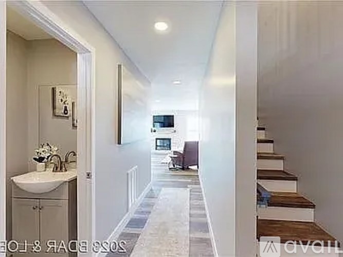 A long hallway with a bathroom on the left and a staircase on the right.