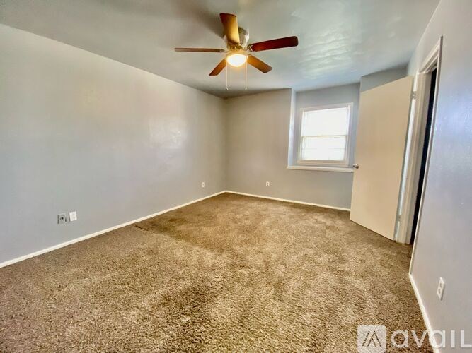 A room with a ceiling fan and carpeted floor.