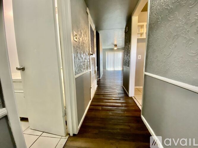 A hallway with a wooden floor and white walls.