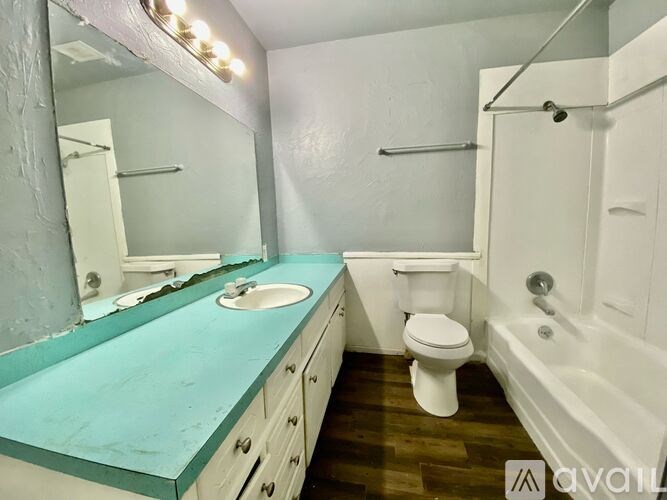A bathroom with a turquoise countertop and white fixtures.