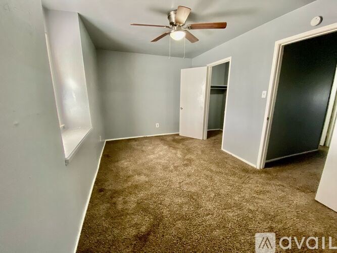 A room with a ceiling fan and carpeted floor.