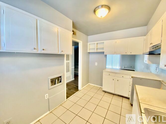 A kitchen with white cabinets and a tiled floor.