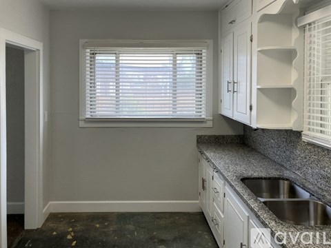 A kitchen with white cabinets and a granite countertop.