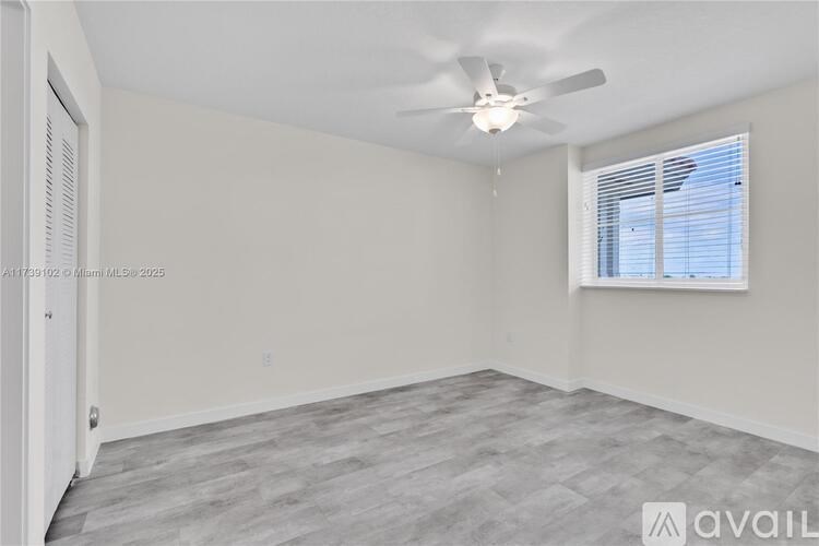 A room with a ceiling fan and a window with blinds.