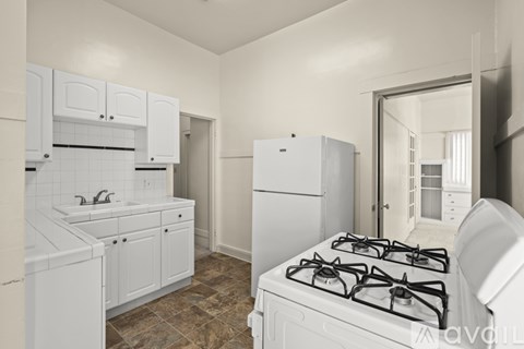 A kitchen with a white gas stove and white cabinets.