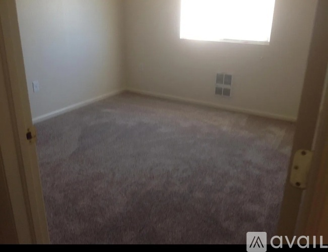 A room with a carpeted floor and a window.