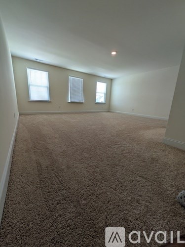 A carpeted room with two windows and a logo on the floor.
