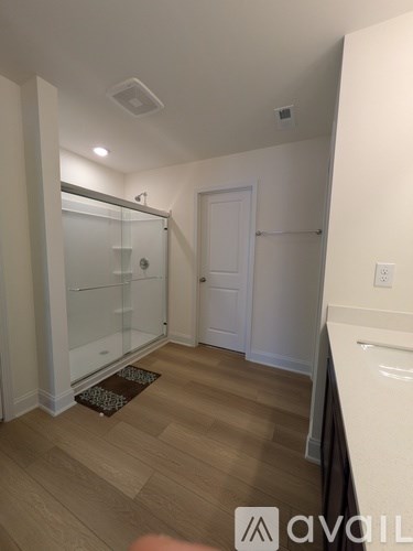A room with a white door and a glass shower stall.