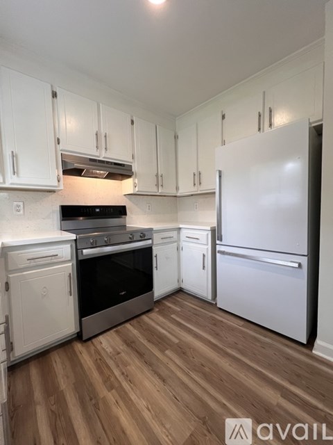 A kitchen with white cabinets and a wooden floor.