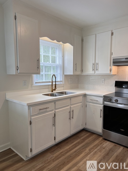 A kitchen with white cabinets and a wooden floor.