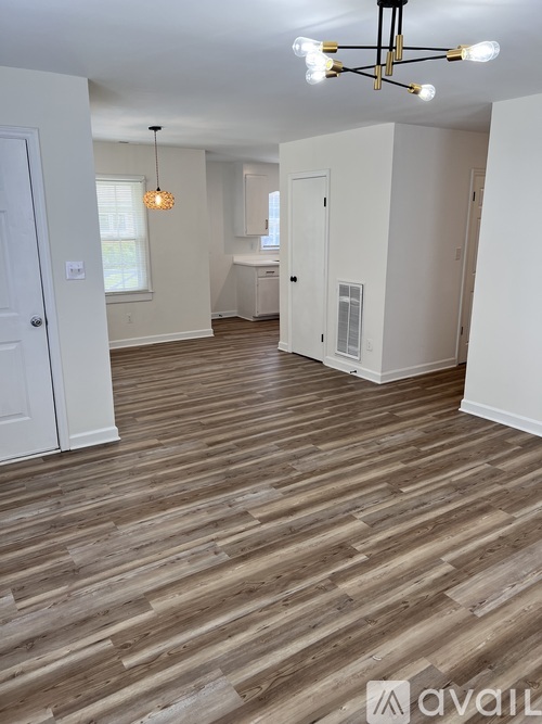 A room with wooden flooring and a chandelier.