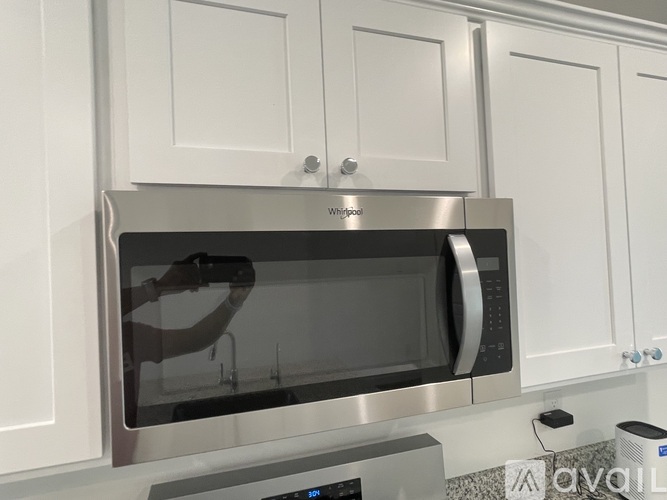 A silver microwave oven is installed in a white cabinet.
