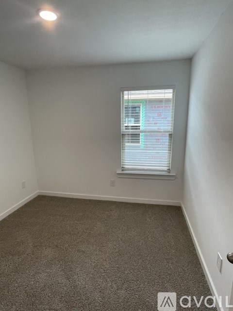 A carpeted room with a window and a door.