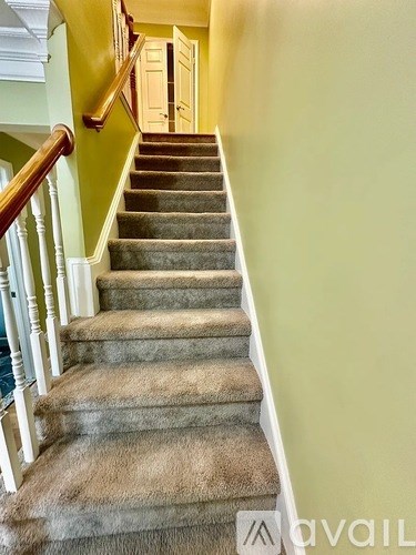 A staircase with a carpeted runner and wooden balusters.