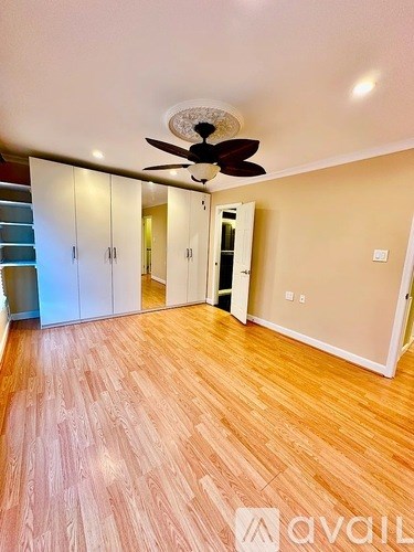 A room with a ceiling fan and wooden flooring.