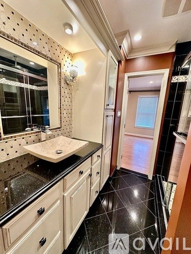 A bathroom with a sink, mirror, and black tile floor.