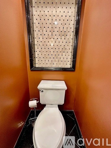 A white toilet with a roll of toilet paper on the side.