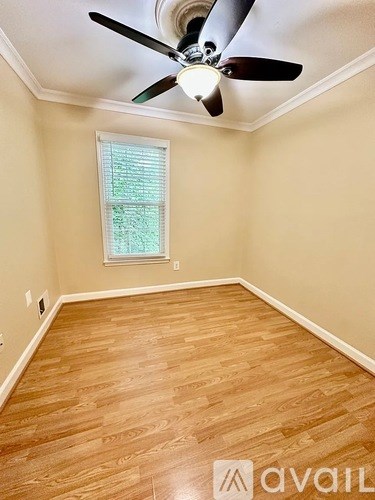 A room with a ceiling fan and wooden flooring.