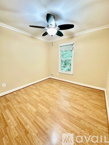 A room with a ceiling fan and wooden flooring.