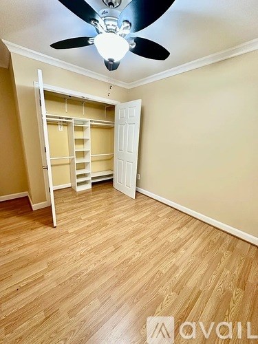 A room with a ceiling fan and wooden flooring.