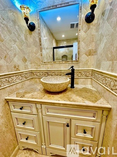 A bathroom with a marble countertop and a round basin.