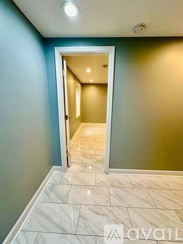 A hallway with a marble floor and a doorway leading to another room.