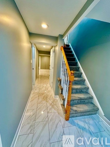 A hallway with a staircase and tiled flooring.
