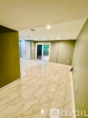 A hallway with a tiled floor and a green wall on the left.