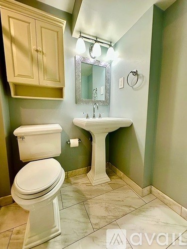 A bathroom with a toilet, sink, and mirror.