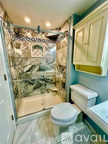 A bathroom with a toilet, sink, and shower with a glass door.