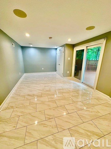 A spacious room with marble flooring and a doorway leading to another room.
